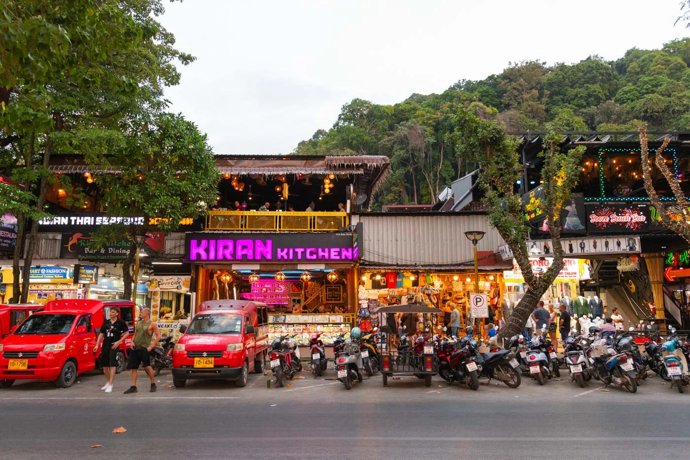 Rue animée de Ao Nang à Krabi avec restaurants et scooters garés devant, ambiance locale vivante