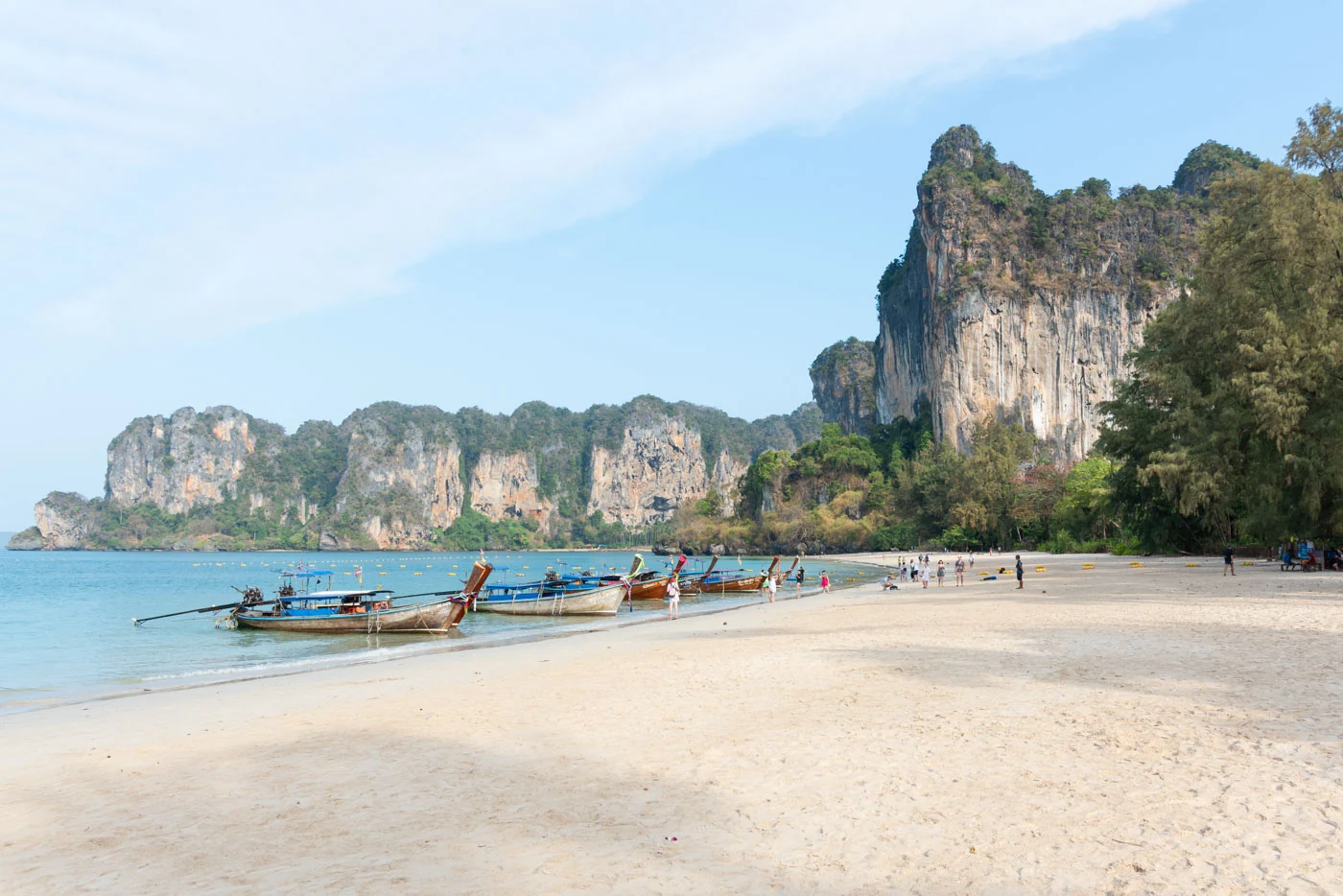 Plage de Railay avec falaises imposantes et bateaux traditionnels amarrés